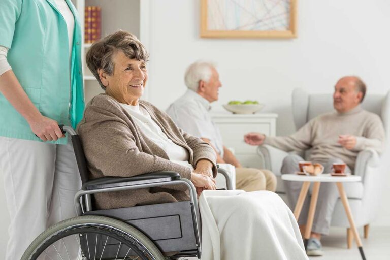 Two older adults and a staff member seated at a table, talking seriously and listening to each other.